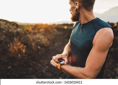 Athletic Runner Start Training On Fitness Tracker Or Smart Watch And Looking Forward On Horizon. Trail Running And Active Lifestyle Concept.