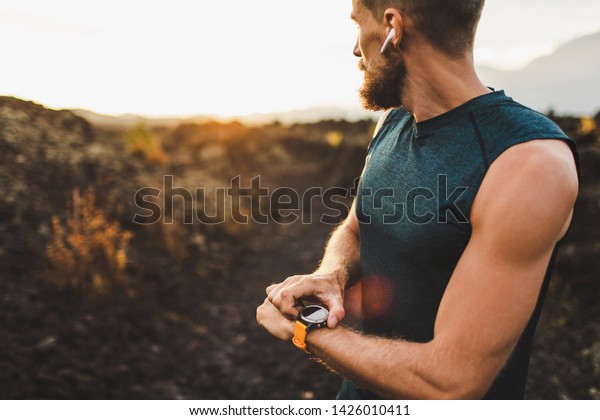 Athletic runner start training on fitness\
tracker or smart watch and looking forward on horizon. Trail\
running and active lifestyle\
concept.