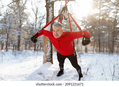 Athletic Senior Man Doing Bungee Fitness Exercises, Training Outdoors On Sunny Winter Morning. Cheerful Mature Sportsman Working Out With Bodyweight Resistance Straps At Snowy Forest