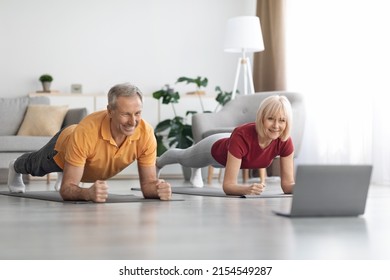 Athletic senior man and woman training at home, smiling mature couple planking together, using modern notebook, watching fitness class on Internet, exercising at home, panorama with copy space - Powered by Shutterstock