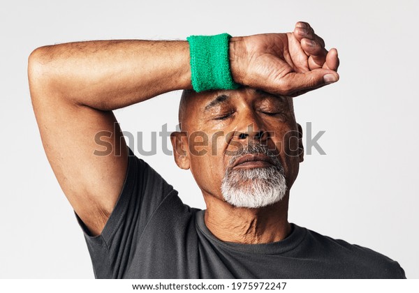 Athletic\
senior mean wiping off sweat from his\
forehead