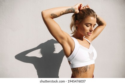 Athletic sports woman tying hair before morning jogging. Female athlete prepare for workout, going on training, exercises outdoors on fresh air spring sunny day, looking determined - Powered by Shutterstock