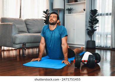 Athletic and sporty man doing warmup and stretching before home body workout exercise session for fit physique and healthy sport lifestyle at home. Gaiety home exercise workout training concept. - Powered by Shutterstock