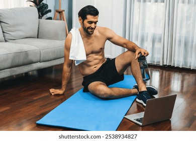 Athletic and sporty man resting on fitness mat during online body workout exercise session for fit physique and healthy sport lifestyle at home. Gaiety home exercise workout training concept. - Powered by Shutterstock