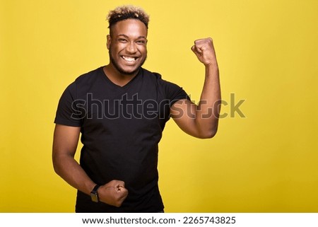 Athletic strong guy brags about his muscles in front of the camera. Brave African-American in a smartwatch shows his muscles and his strength with his mouth wide open. 