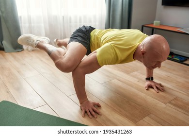 Athletic Strong Man Having Training At Home, Standing On His Arms And Legs In The Air. Hard Yoga Pose. Fitness, Healthy Lifestyle, Stay Home Concept