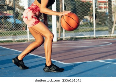 Athletic tanned woman playing basketball on the sports field in summer, Close-up of a woman's legs playing basketball - Powered by Shutterstock