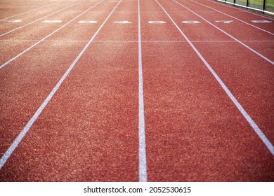 Athletic track in natural light with long numbered lanes to the horizon gives the feeling of preparedness focus and direction, with no people, and copy space - Shutterstock ID 2052530615