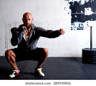 Athletic white man doing squats while lifting kettlebells - Powered by Shutterstock