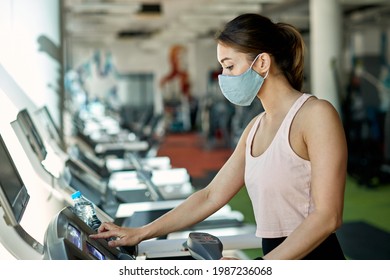 Athletic Woman Adjusting Speed On Treadmill While Having Sports Training At Health Club During Coronavirus Pandemic.