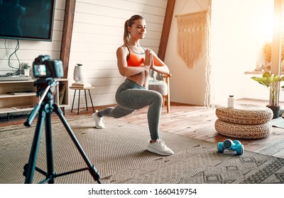 Athletic woman blogger in sportswear shoots video on camera as she does exercises at home in the living room. Sport and recreation concept. Healthy lifestyle. - Powered by Shutterstock