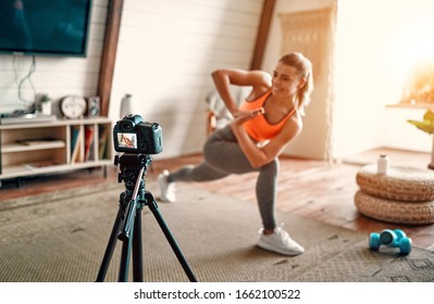 Athletic woman blogger in sportswear shoots video on camera as she does exercises at home in the living room. Sport and recreation concept. Healthy lifestyle. - Powered by Shutterstock