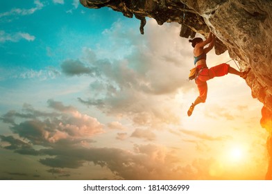 Athletic Woman climbing on overhanging cliff rock with sunset sky background - Powered by Shutterstock