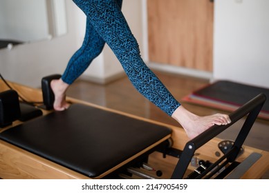 An Athletic Woman Does An Exercise On A Reformer In The Gym.No Face. Feet Close-up On The Reformer.Pilates.The Concept Of A Healthy . High Quality Photo