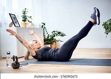 Athletic woman doing abs exercise hollow body during home workout - Shutterstock ID 1760392673