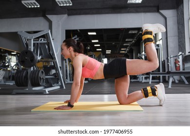 Athletic Woman Doing Donkey Kick Exercise At The Gym, Wearing Ankle Weights