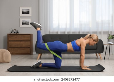 Athletic woman doing exercise with fitness elastic band on mat at home - Powered by Shutterstock