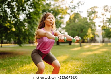 Athletic woman doing exercises with dumbbells outdoors on a sunny day. Sports concept. Active lifestyle. - Powered by Shutterstock