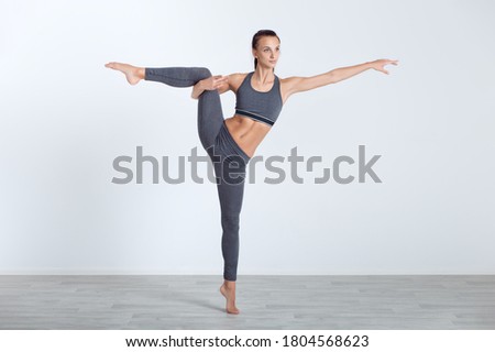 Athletic woman doing fitness exercise on white wall