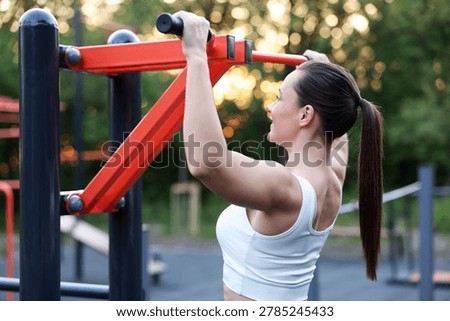 Athletic woman doing pull ups at outdoor gym