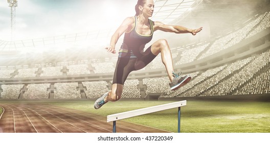 Athletic woman doing show jumping against view of a stadium