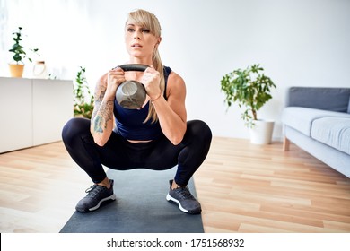 Athletic Woman Doing Strength Workout With Kettlebell At Home