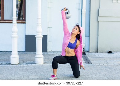 Athletic Woman Exercising Turkish Get Up With Kettlebell In The City