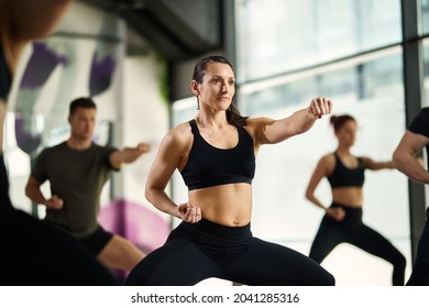 Athletic woman in fighting stance exercising hand punches during martial arts training at health club.