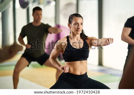 Athletic woman in fighting stance practicing martial arts during exercise class at health club. 