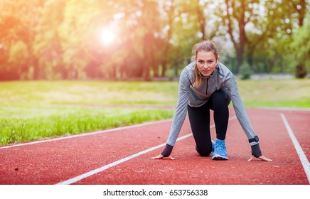 Athletic Woman On Running Track Getting Ready To Start Run