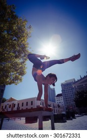 Athletic woman performing handstand on bench in the city