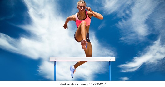 Athletic woman practicing show jumping against blue sky with clouds - Shutterstock ID 437225017