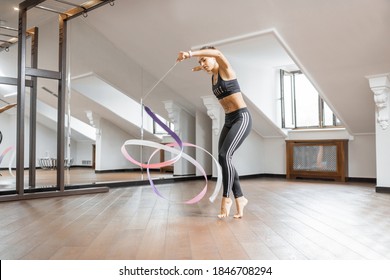 Athletic Woman Practising Rhythmic Gymnastics With A Ribbon In The Gym