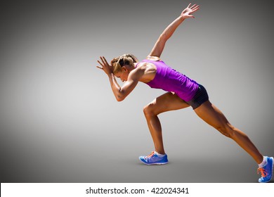 Athletic woman preparing to run against grey vignette