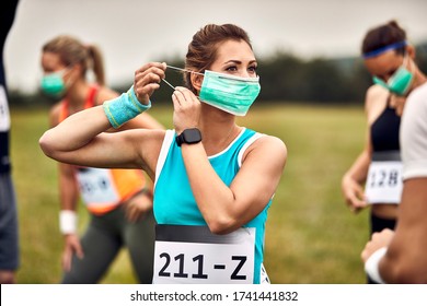 Athletic woman putting on face mask while participating in marathon race in nature. - Powered by Shutterstock