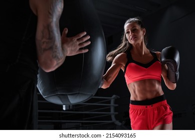 Athletic Woman In Red Shorts And Top Is Boxing With A Trainer. Boxing And Mixed Martial Arts Concept. Mixed Media