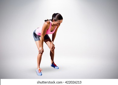 Athletic woman resting with hands on knees against grey background - Shutterstock ID 422026213