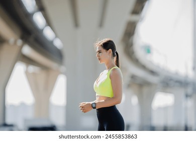 Athletic woman resting, urban bridge background, sunny. - Powered by Shutterstock