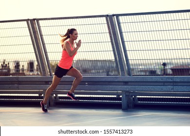 Athletic Woman Running On Rooftop At Sunset, Dusk In The City