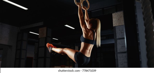 Athletic woman in sports top and shorts working out on gymnastic rings at the crossfit gym sportswear equipment strength body beauty power muscles improving lifestyle activity. Crossfit and fitness  - Powered by Shutterstock