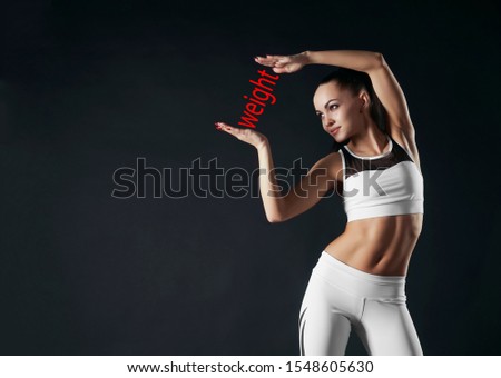 Athletic woman in sports wear presenting something on open palm.  girl with open hands. Beautiful female showing word weight between palms.  inscription between hands. 