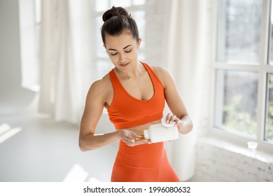 Athletic woman takes supplements or vitamins in the form of capsules after training in the gym. Concept of additional nutrition during training