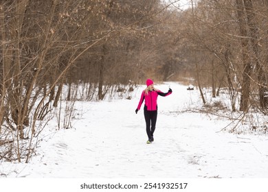 Athletic woman taking selfie with her smartphone and wearing headphones while jogging on a bridge during winter snowy day. Healthy lifestyle, winter fitness, cold weather. - Powered by Shutterstock