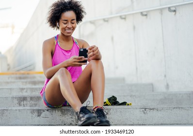 Athletic Woman Using Her Mobile Phone Outdoors.