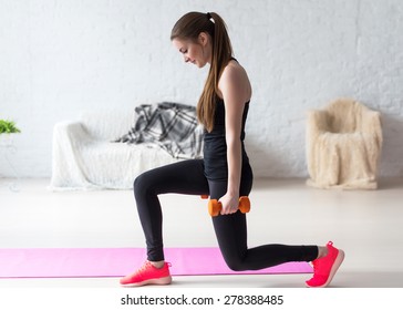 Athletic woman warming up doing weighted lunges with dumbbells workout exercise for butt legs at home healthy lifestyle sport bodybuilding concept.