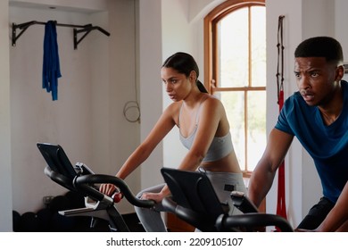 Athletic Young Biracial Woman And Black Man Doing Cardio Exercise Bike At The Gym