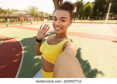 Athletic young black lady waving at smartphone screen, having online conference with fitness trainer, millennial sports influencer recording video blog. Pretty woman greeting instructor or followers - Powered by Shutterstock