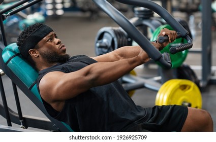 Athletic Young Black Man Having Workout On Chest Press Machine In Gym, Pushing Weight While Reclining On Bench, Building Up Arms And Torso Muscles, Side View, Panorama, Closeup