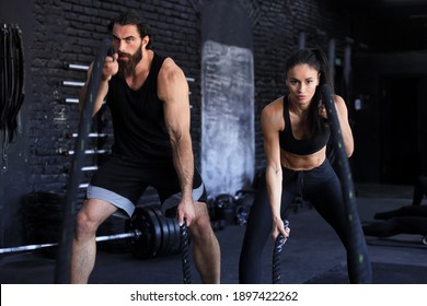 Athletic Young Couple With Battle Rope Doing Exercise In Functional Training Fitness Gym
