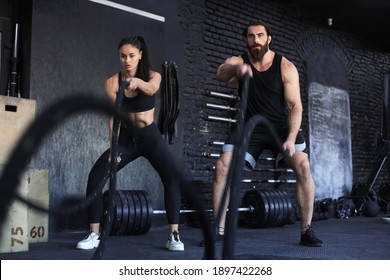 Athletic young couple with battle rope doing exercise in functional training fitness gym - Powered by Shutterstock